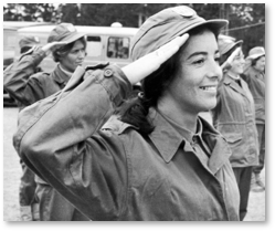 Sort-hvitt bilde av smilende kvinne i uniform som gjør honnør.